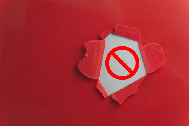 赤い背景から破れる注意マーク